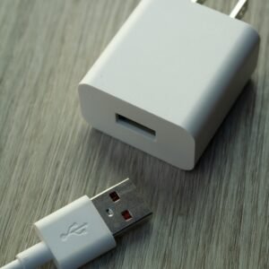 A detailed view of a white USB charger and cable on a wooden surface.