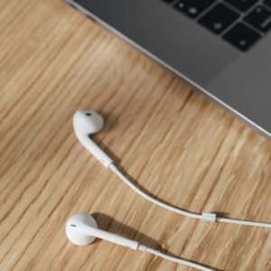 A modern desk setup with a laptop and white earphones on a wooden surface.